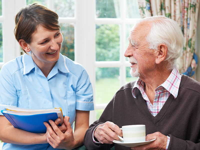 Affinity Homecare about page. Carer chatting with an elderly gentleman over a cup of tea